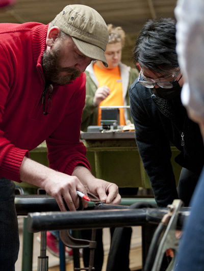 Two people work on a design project that involved the base of a metal table.