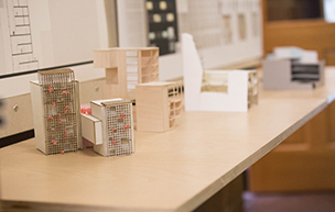 Models of buildings are positioned on a desk.