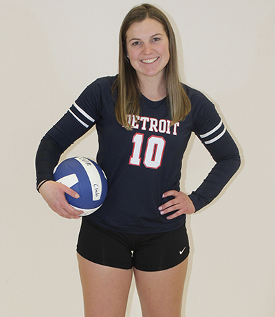 Kirstin Finnila poses for a photo in her volleyball uniform while holding a volleyball by her hip.