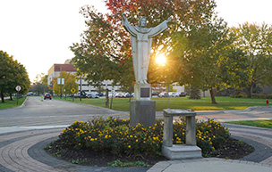 The Jesus statue on the McNichols Campus at sunrise during the fall.