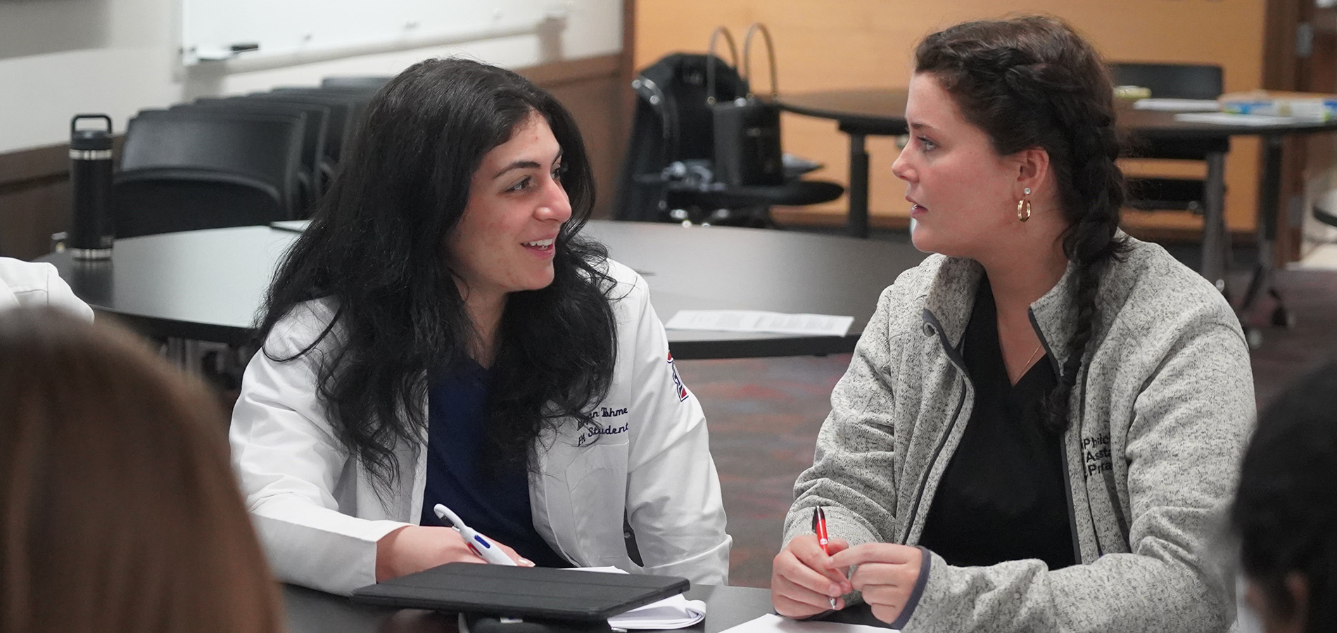 Two PA students sit at a table during a class project.