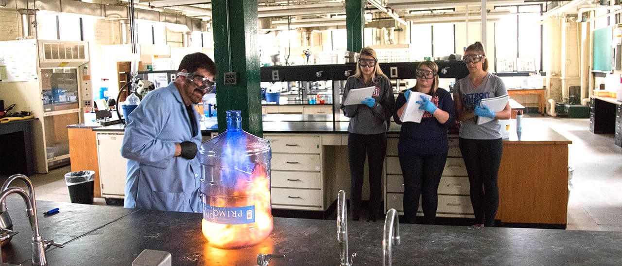 chem student with professor making a fireball in a clear container
