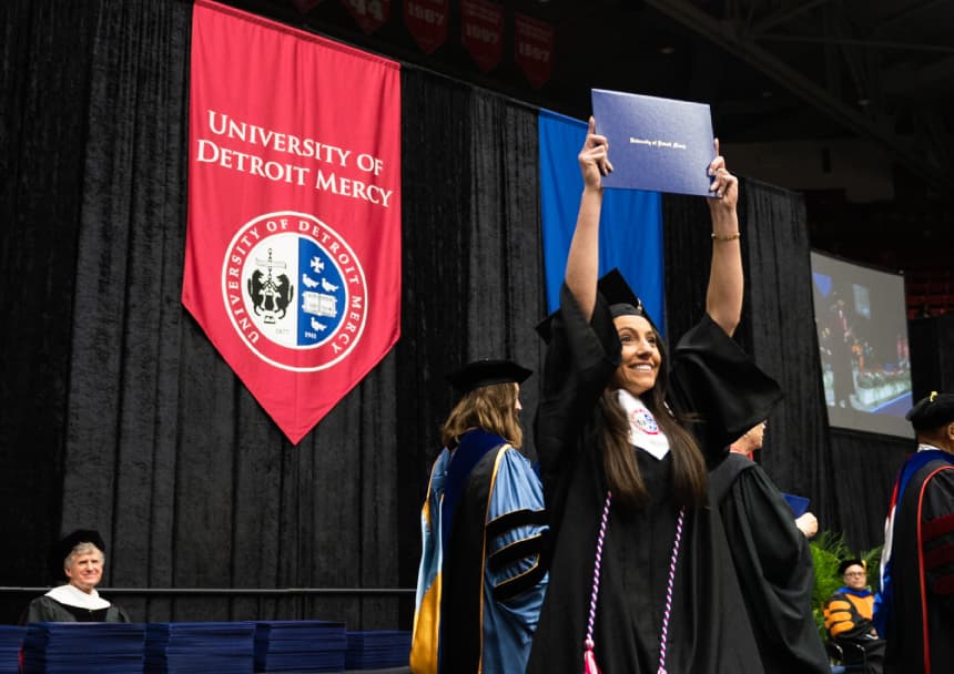 A graduate poses with her diploma at commencement.