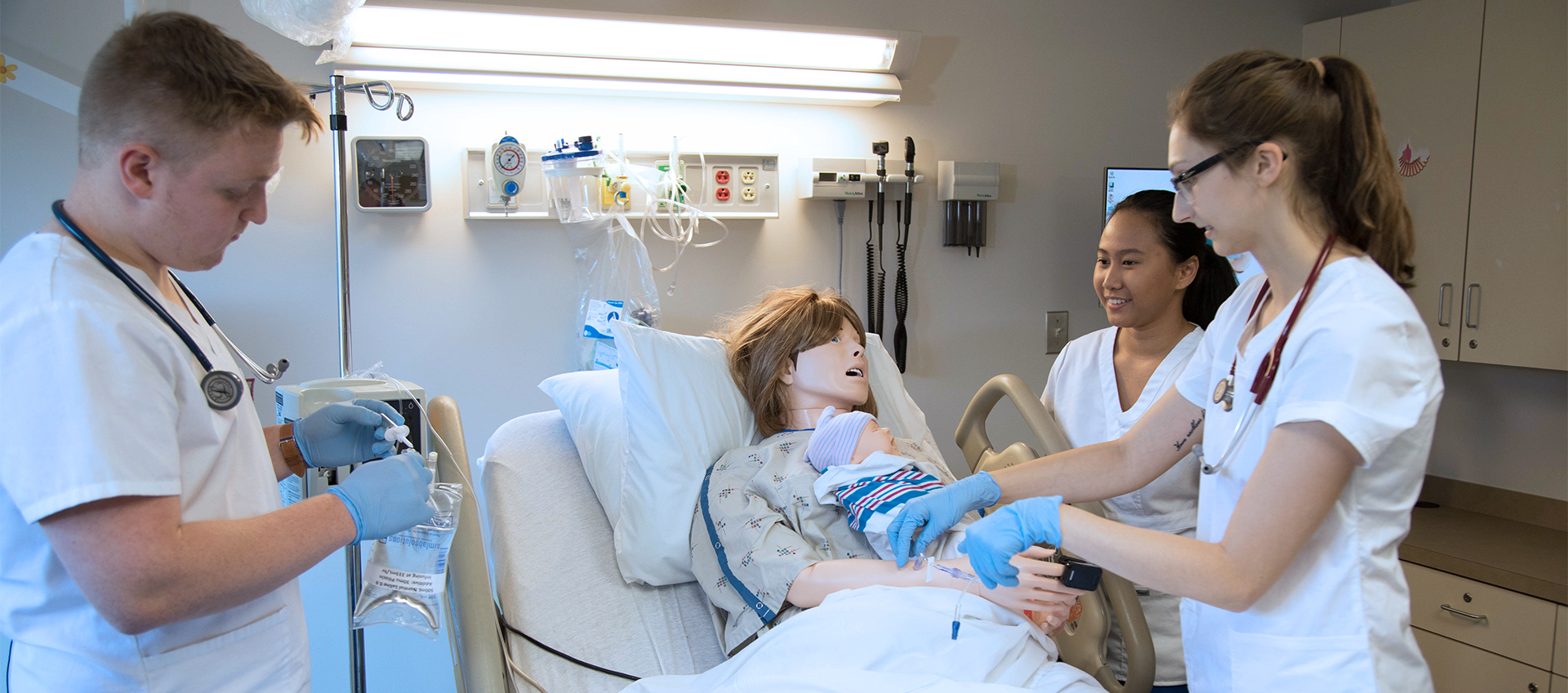 CHP students practice bedside manner with a mannequin and mannequin baby.