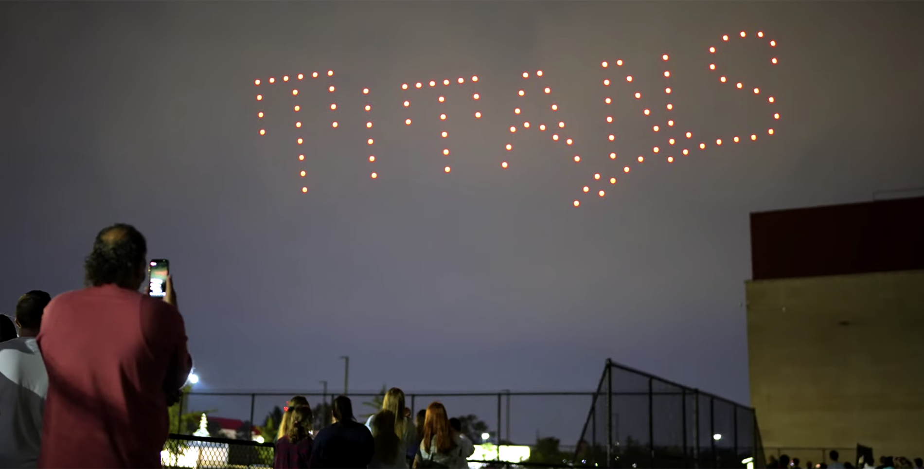 Students watch as a drone show lights up the McNichols Campus sky with the word Titans