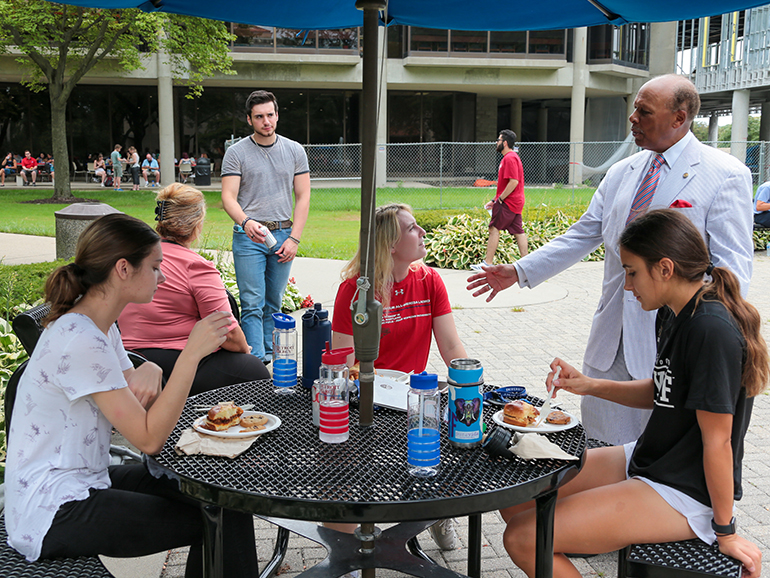 President Antoine M. Garibaldi talks to a group of female students during first-year convocation's lunch.