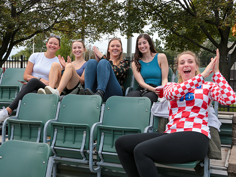 A group of female students cheer during the Homecoming 2021 softball tournament.