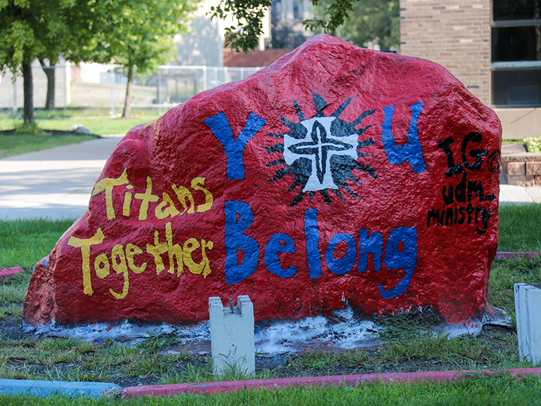 The rock on Detroit Mercy's campus is painted for move-in day. Text on the rock reads: Titans Together. You Belong Here. IG: @udm_ministry