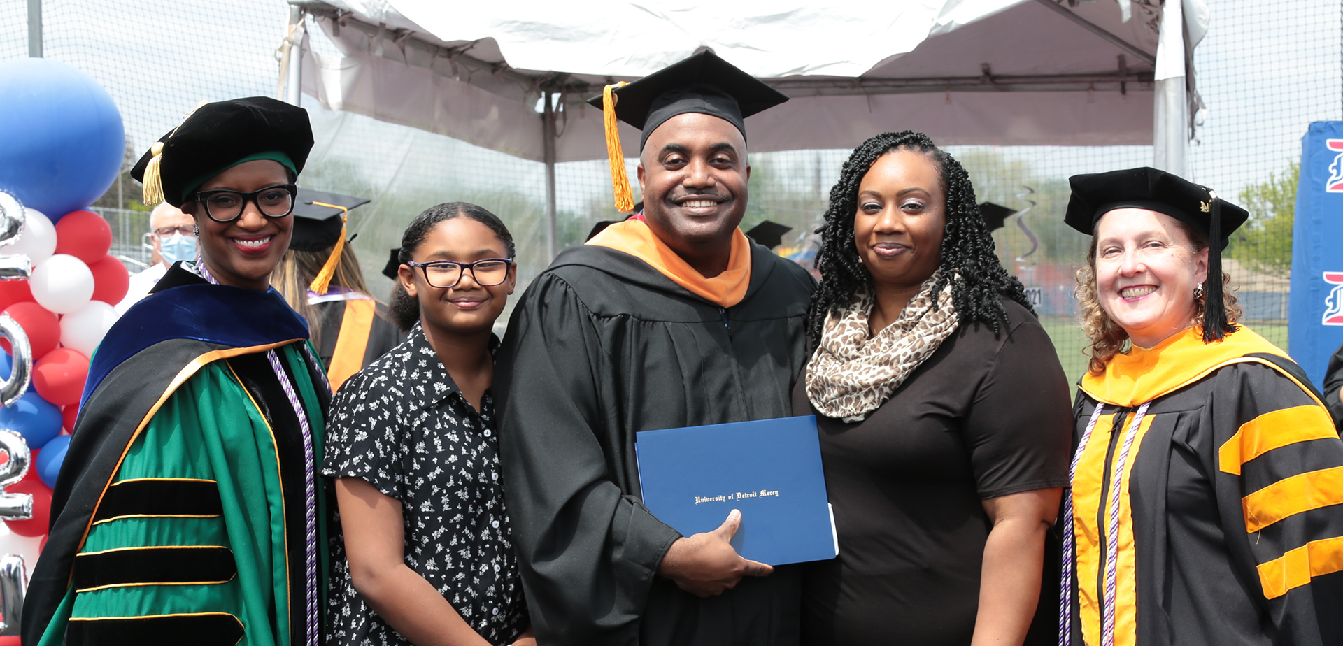 Graduate smiles with his family at on-campus celebration.