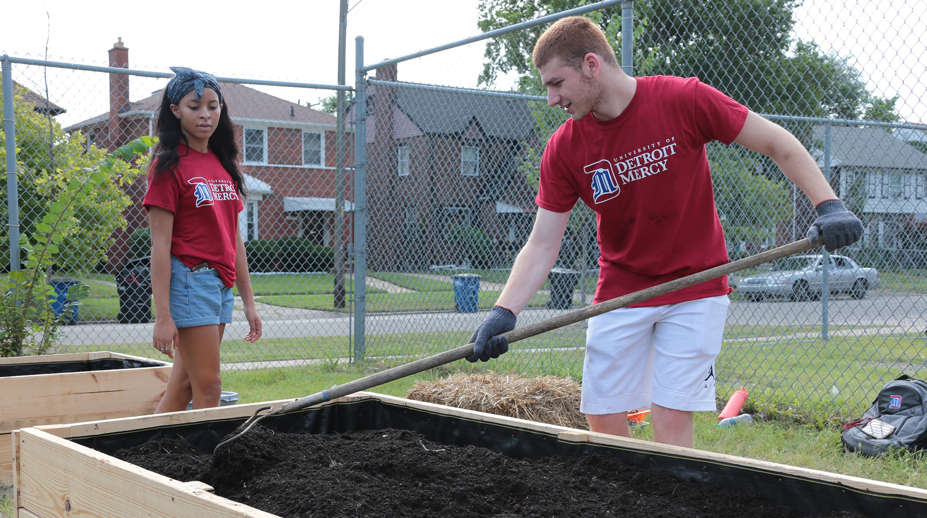 A pair of Detroit Mercy students shovel mulch during the annual service work portion of PTV.