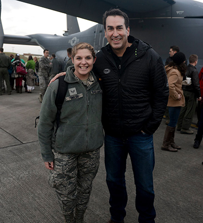 A photo of Victoria Taylor with actor Rob Riggle underneath the wing of a military aircraft.