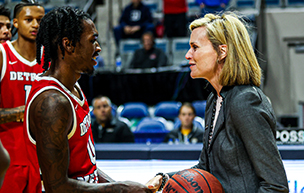 Antoine Davis, left, shakes hands with Horizon League commissioner Julie Roe Lach, who holds a basketball.