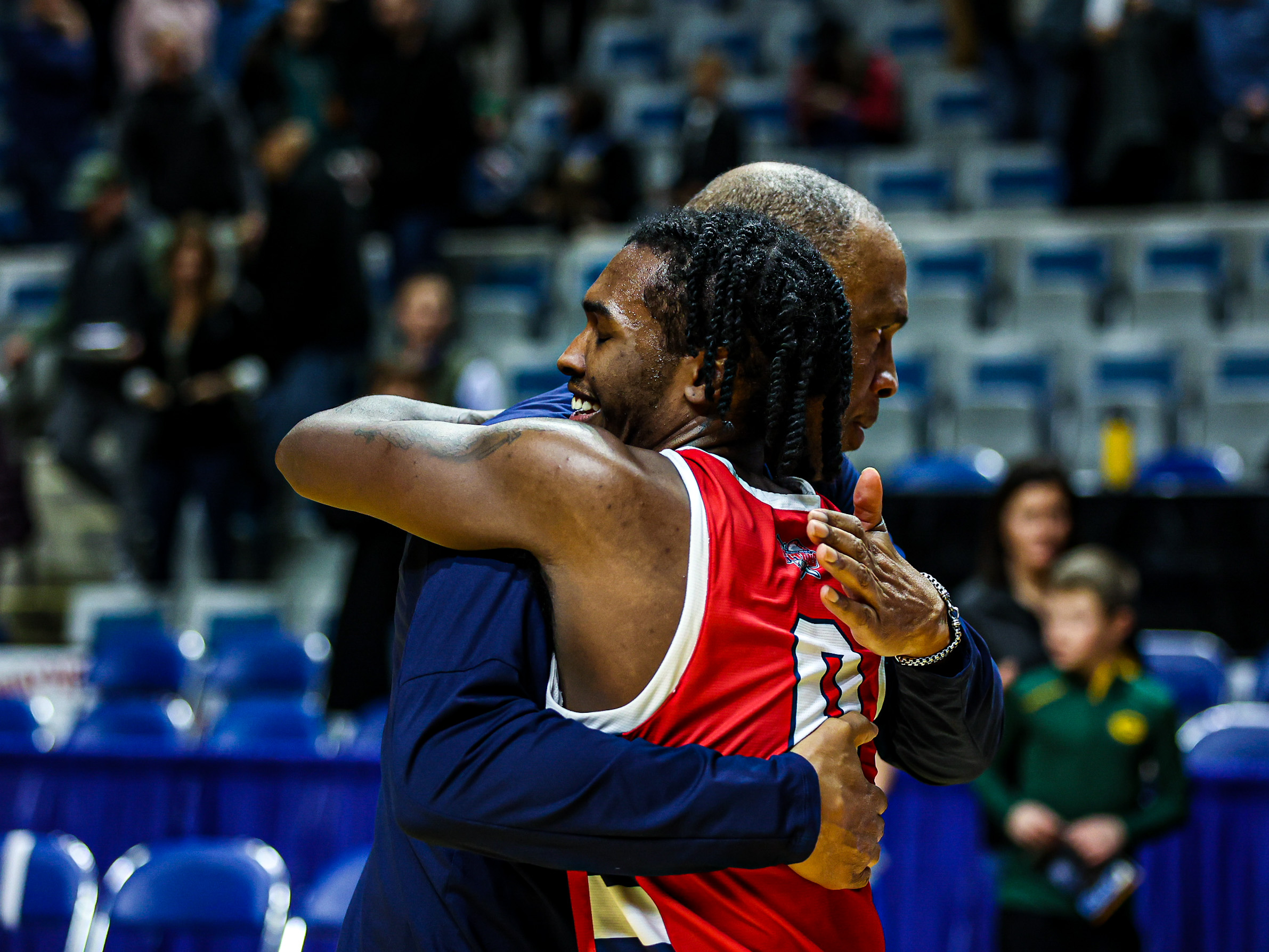Antoine Davis, left, hugs his father, Mike Davis, inside of a basketball arena.