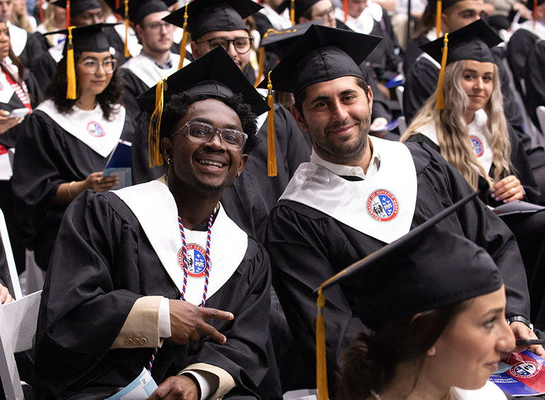 Graduates smile and pose for a photo during commencement.