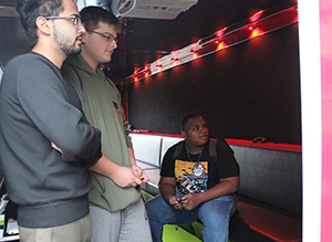 Students sit in a portable gaming trailer and play Super Smash Bros. Ultimate during an esports club tournament.
