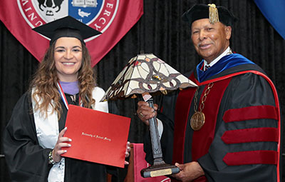 President Antoine M. Garibaldi presents Taylor Lynn Kile with the Vivere ex Missione award during commencement.