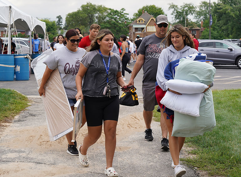 A group of students and their families carry belongings from the parking lot to Shiple Hall during freshman move-in day.