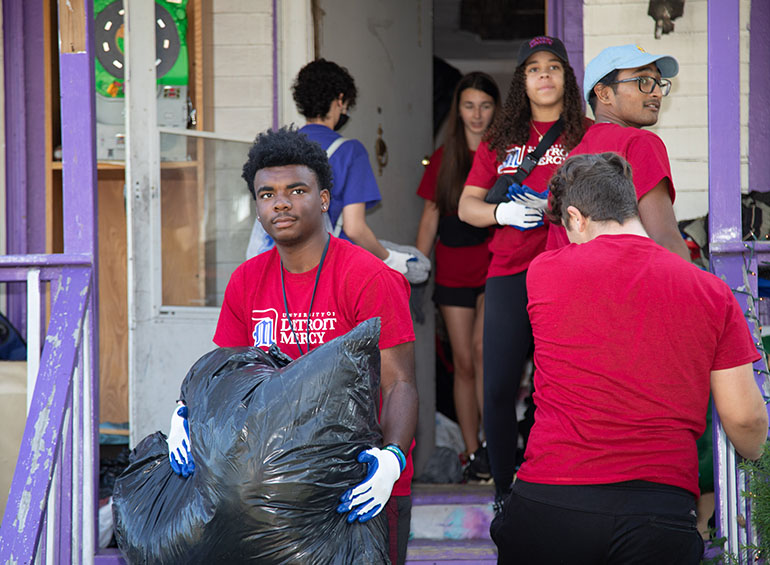 Students carry out bags of clothes out of a house on Detroit's west side.