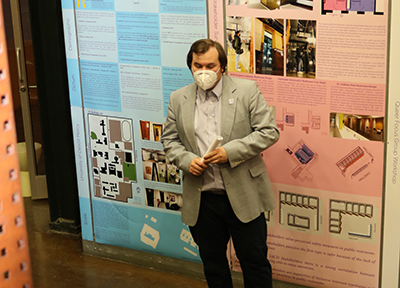 Joseph Silveira stands in front of his architecture presentation, which features various blueprints, layouts and images.