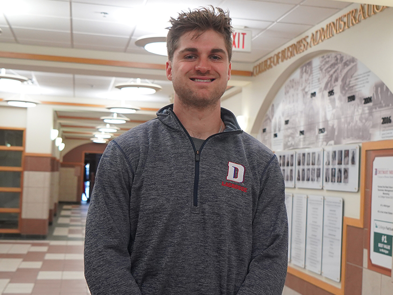 Ryan Birney stands smiling inside of the Commerce and Finance Building.