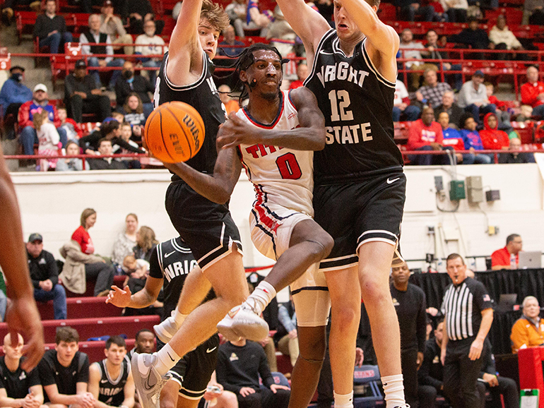 Antoine Davis passes the ball between a pair of Wright State players inside of Calihan Hall.