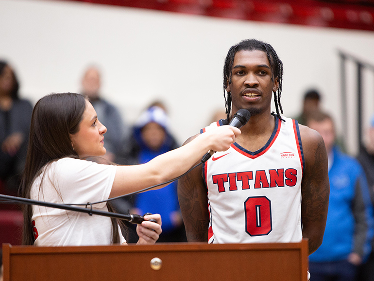 Kara Wolfbauer, left, interviews Antoine Davis near a podium inside of Calihan Hall.