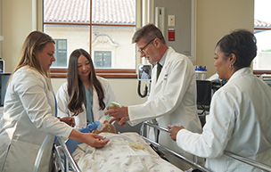 Four people stand and work on a mannequin patient inside a classroom of the STAR simulation center.