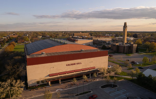 An aerial shot of Calihan Hall with the rest of campus, including the clocktower, visible in the background.