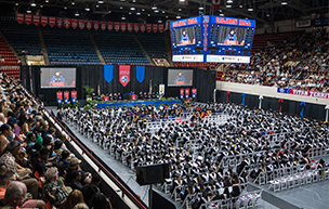 Hundreds of graduates and others sit inside of Calihan Hall during a commencement ceremony.
