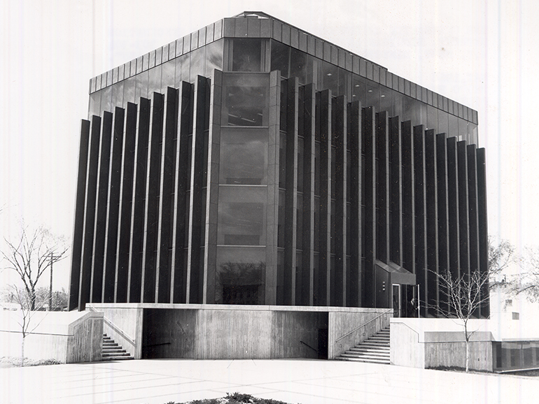 A black and white photo shows the Fisher Administration Building with sidewalks and stairs leading up to it.