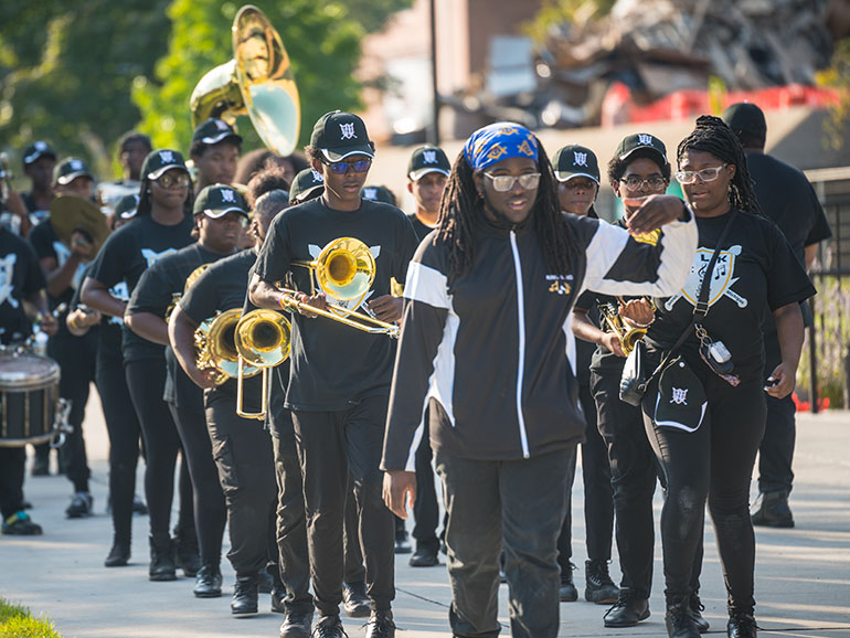A local high school's band walks together with their instruments on Detroit Mercy's McNichols Campus.