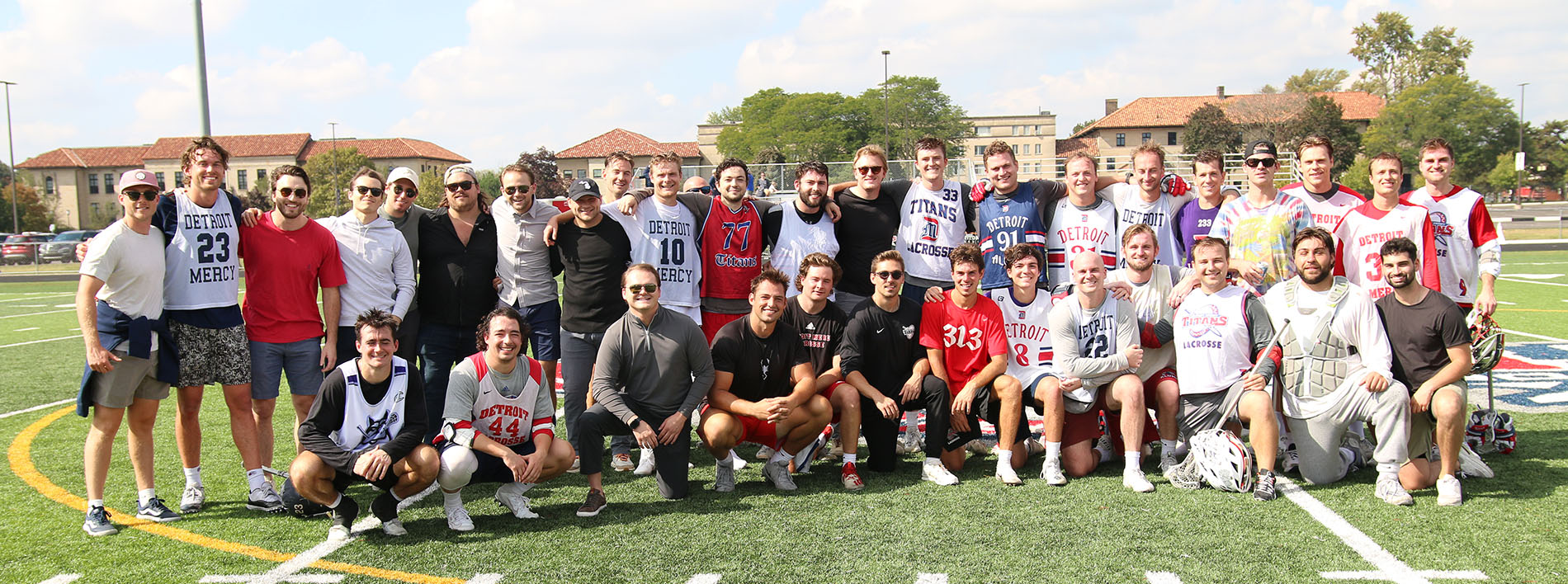 Detroit Mercy men's lacrosse student-athletes and alumni pose for a team photo on Titan Field after the alumni game.