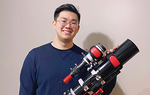 Janson Fu stands behind his astrophotography equipment for a photo.