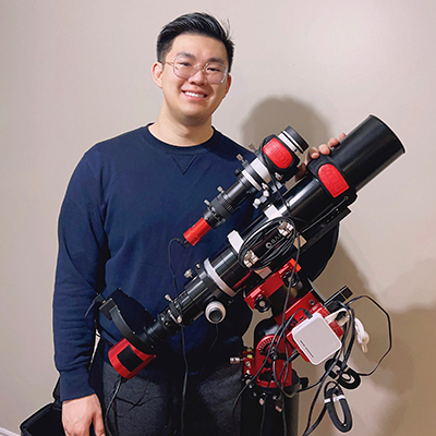 Janson Fu stands behind his astrophotography equipment for a photo.