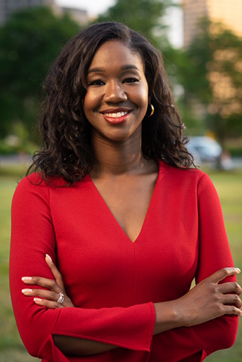 Kyra Harris Bolden smiling outdoors in a red dress