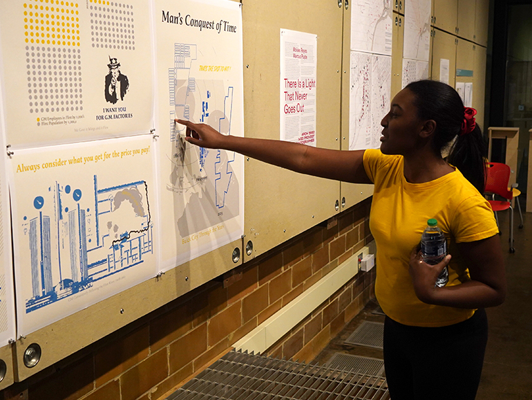 Angel Mangham points out something on a class project that is displayed on a wall inside of the School of Architecture.