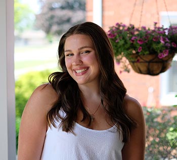 Mary Courtright smiles for a photo in front of a basket of flowers.