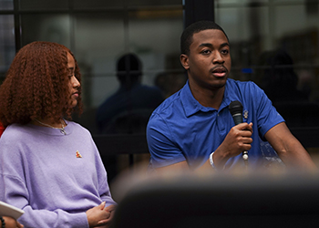 A woman listens as a man talks during an MLK panel discussion.