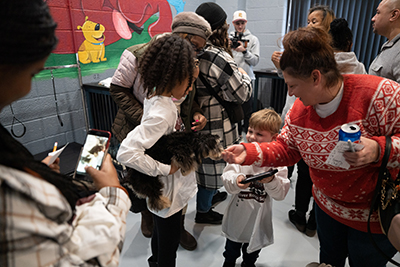 At the Pup Culture Lab's grand opening, people interact with each other as a child holds a dog.