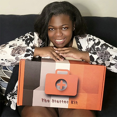 Shawna Stewart '15 poses for a photo while holding a box containing The Starter Kit, which she created for nursing students.