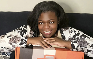 Shawna Stewart '15 poses for a photo while holding a box containing The Starter Kit, which she created for nursing students.