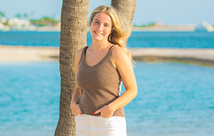 Keagan Tremel poses for a photo in front of a palm tree on a beach.