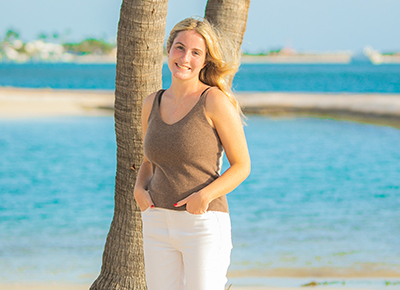 Keagan Tremel poses for a photo in front of a palm tree on a beach.