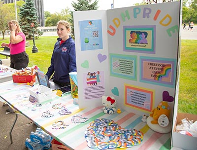 A student stands next to UDM Pride's display at this year's Titan Fest event on the McNichols Campus.