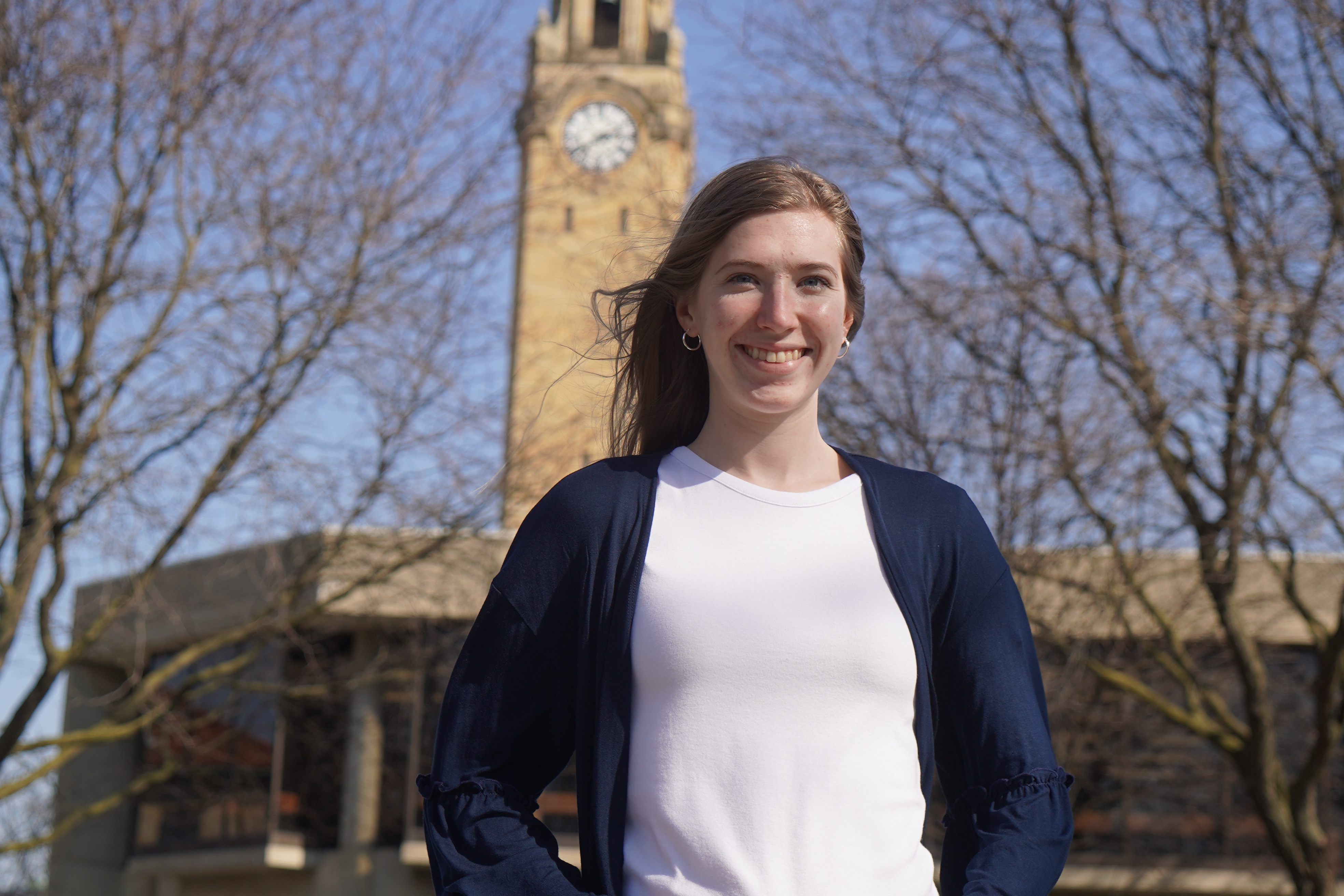 Patterson stands outdoors in front of the Student Union and clock tower.