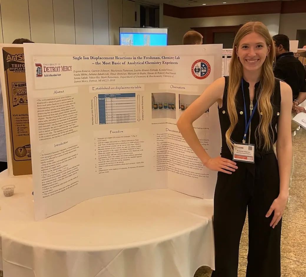 MacKenzie Patterson stands indoors next to a poster display.