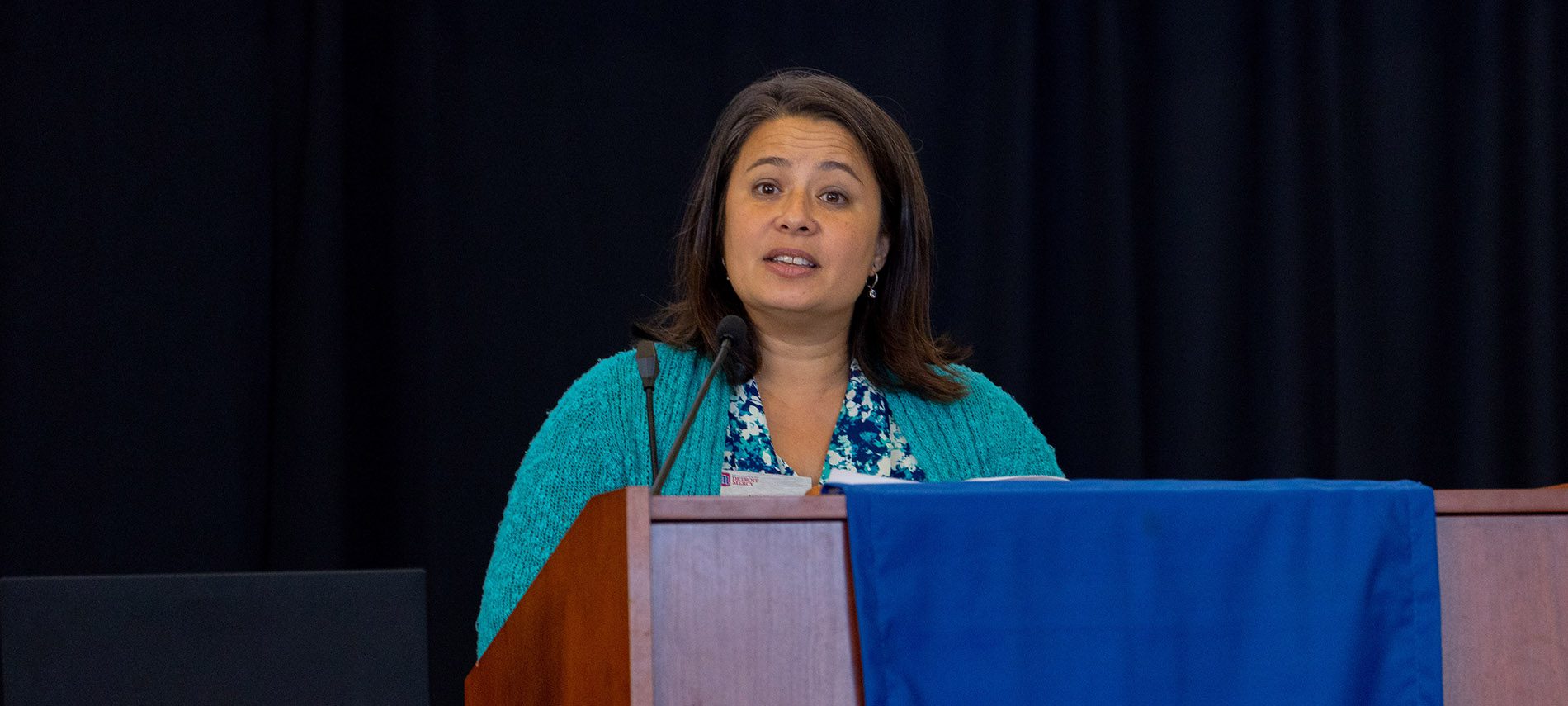 Anita Klueg speaks at a podium.