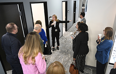 A woman talks to people by a hall of exam rooms as they tour the Eye Institute.