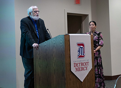 Roy Finkenbine speaks at the podium while Ilyon Woo stands next to him during Love Stories from the Underground Railroad in February 2024.