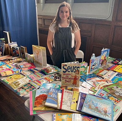 Erin Letourneau poses behind a table filled with books.